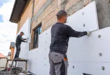 Будівельники монтують утеплювач на фасад приватного будинку
